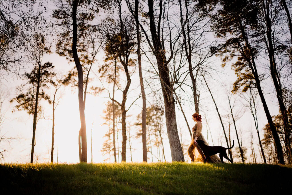 Woman walking her dog along a peaceful lake trail at sunset.