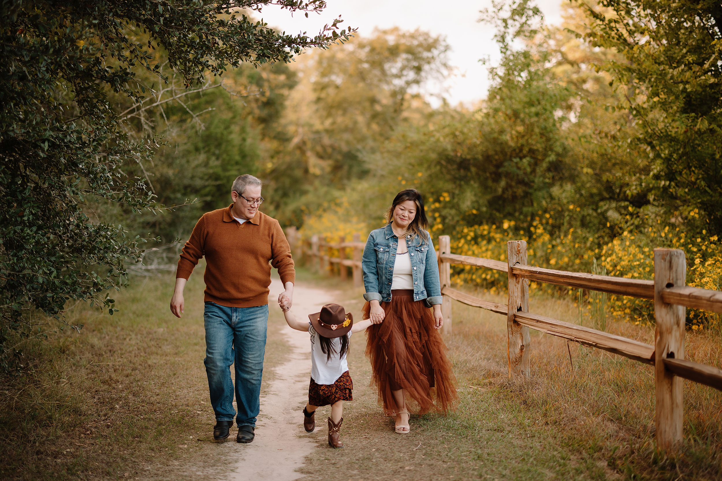 Family walking hand in hand on a nature trail in The Woodlands area.