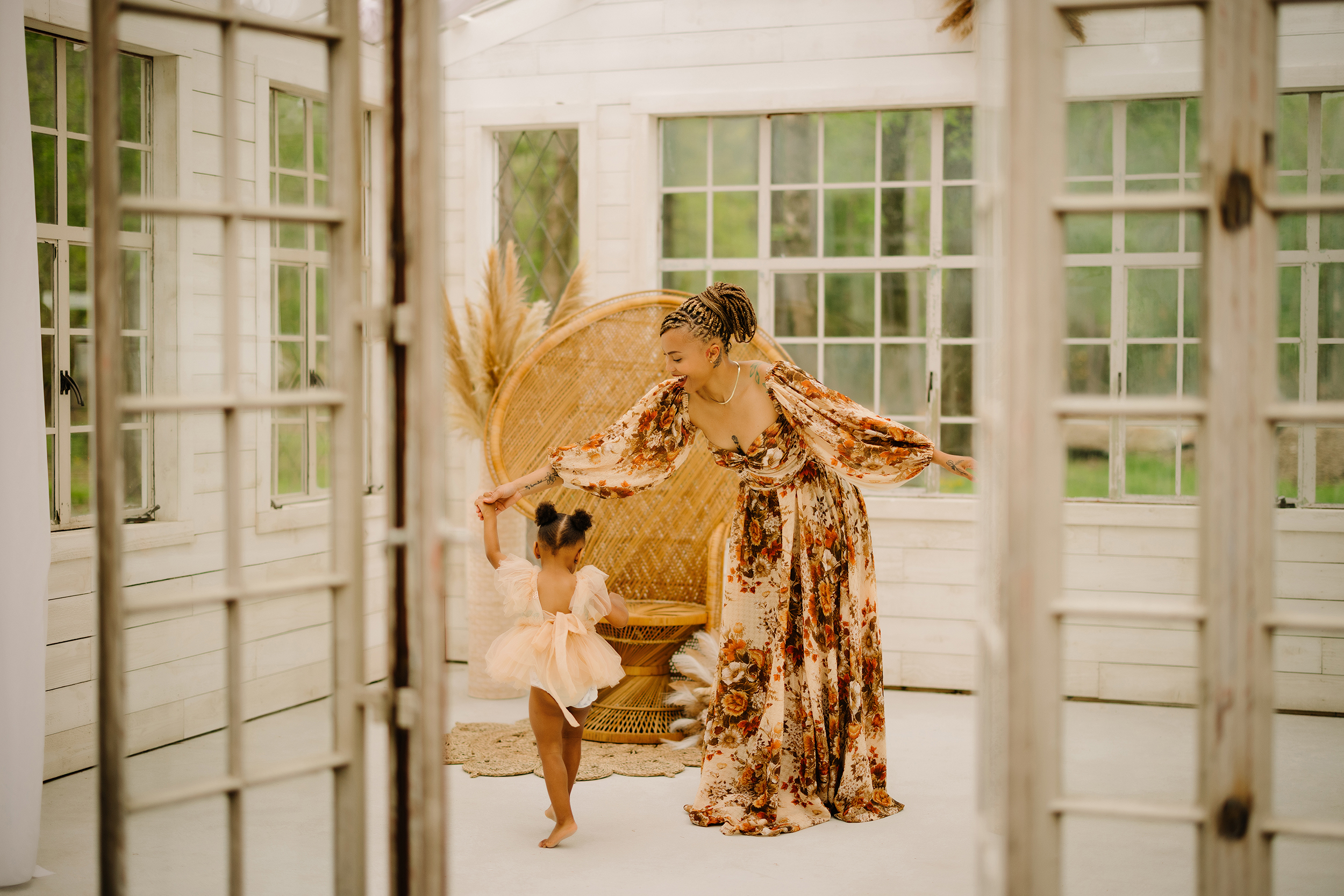 Beautiful mother and daughter in a sunlit open field with magnolia trees.