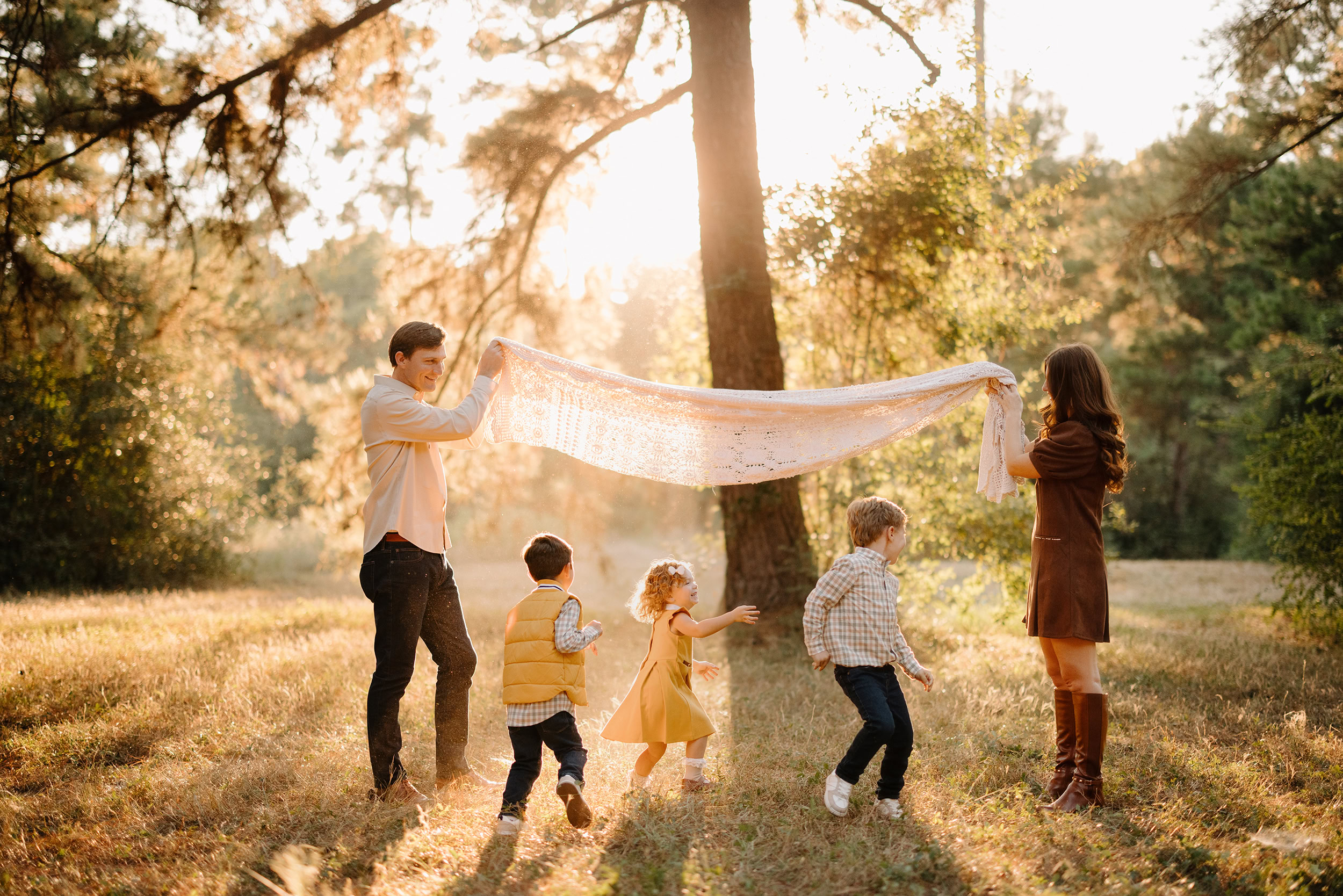 Family playing with a blanket in Tomball Pines during sunset.