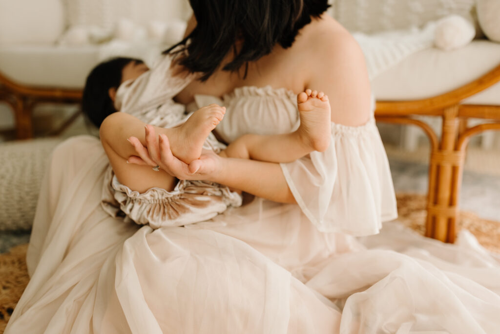 Mother breastfeeding her baby on a cozy, neutral-toned sofa.