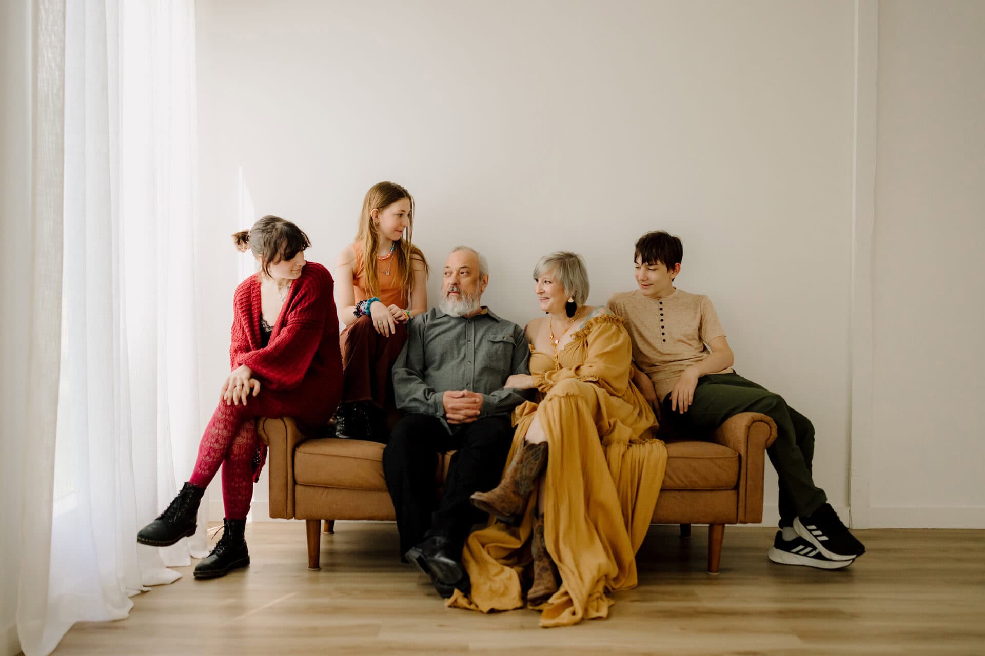 Family portrait of five people sitting on a sofa in a bright, modern living room.
