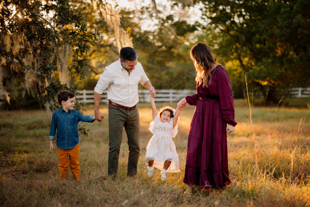 family of four playing in a field under golden light