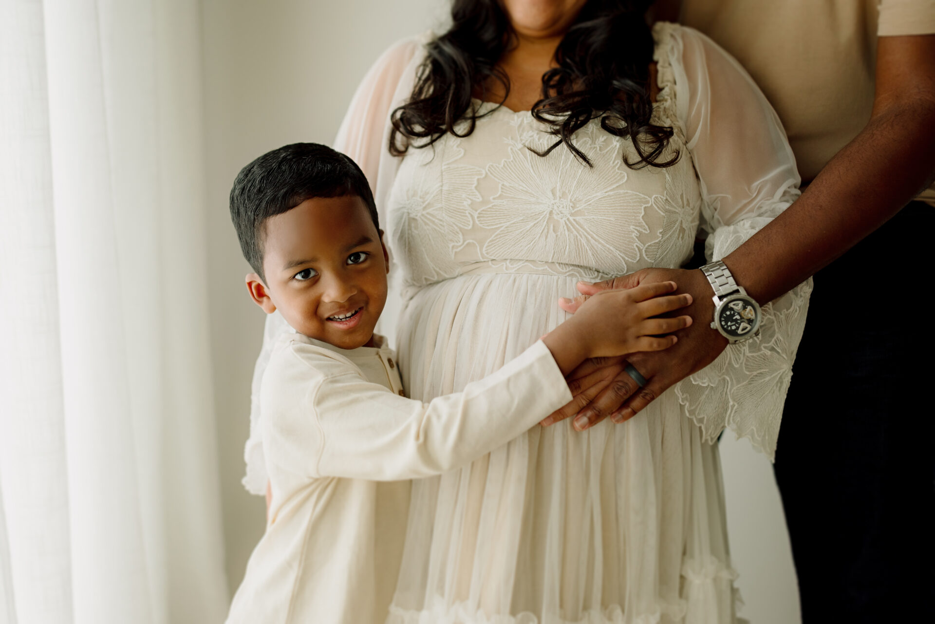 Pregnancy portrait of a woman with her young son and partner in a cozy home setting.