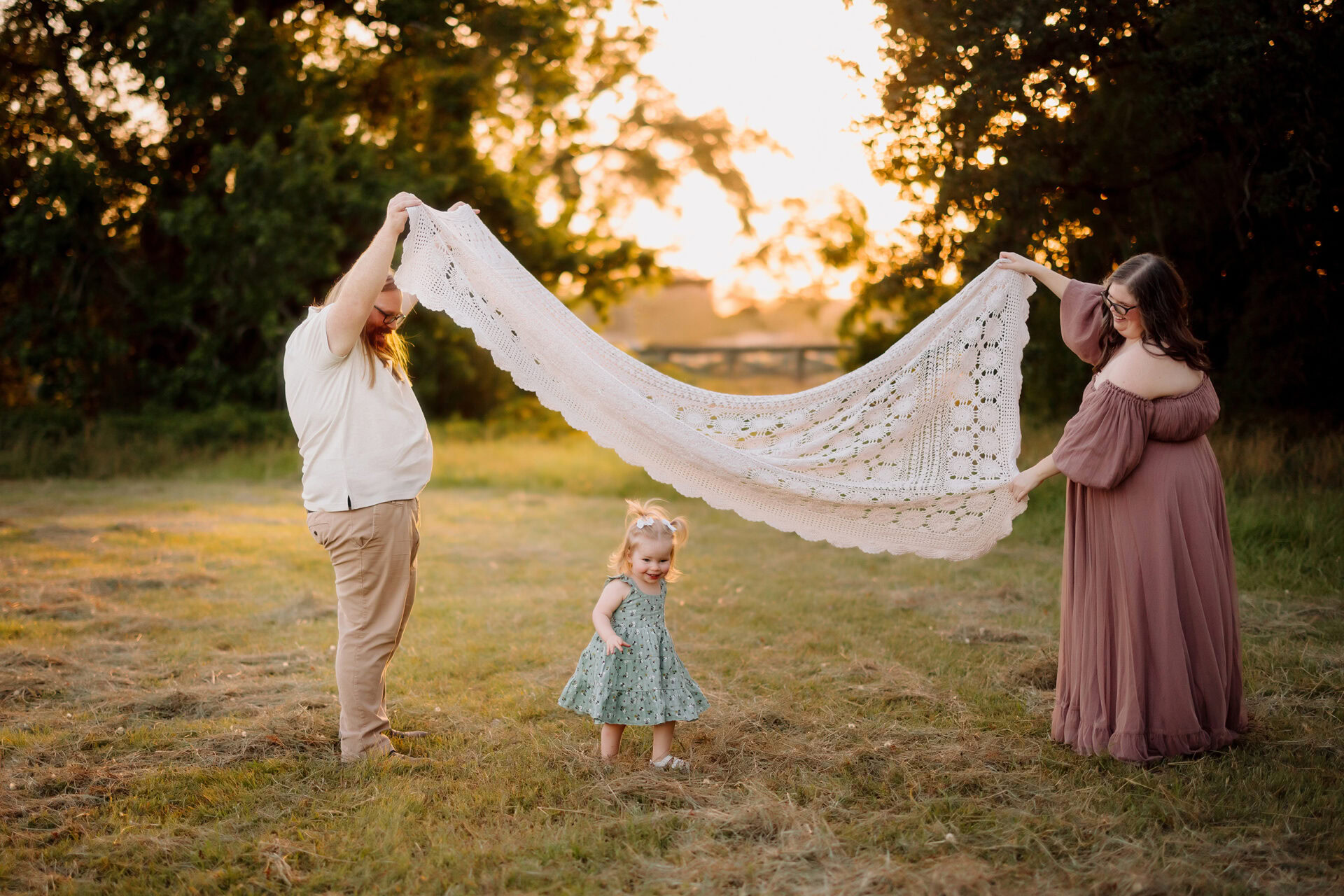 Family outdoor photo with a blanket in a natural setting at sunset.