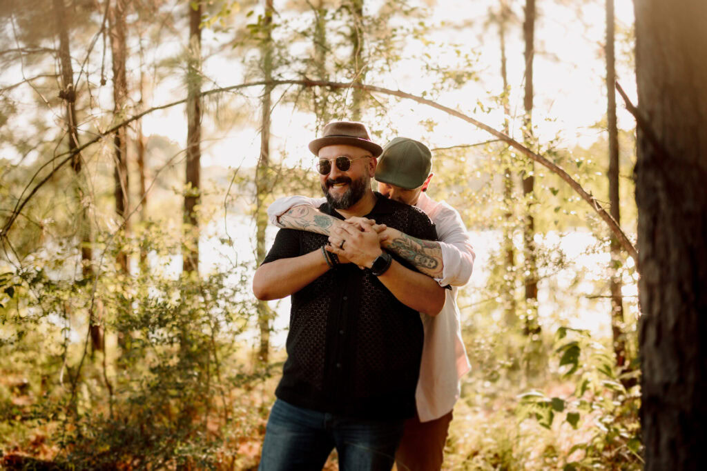 Happy family embracing in a sunlit forest, capturing joyful moments outdoors.