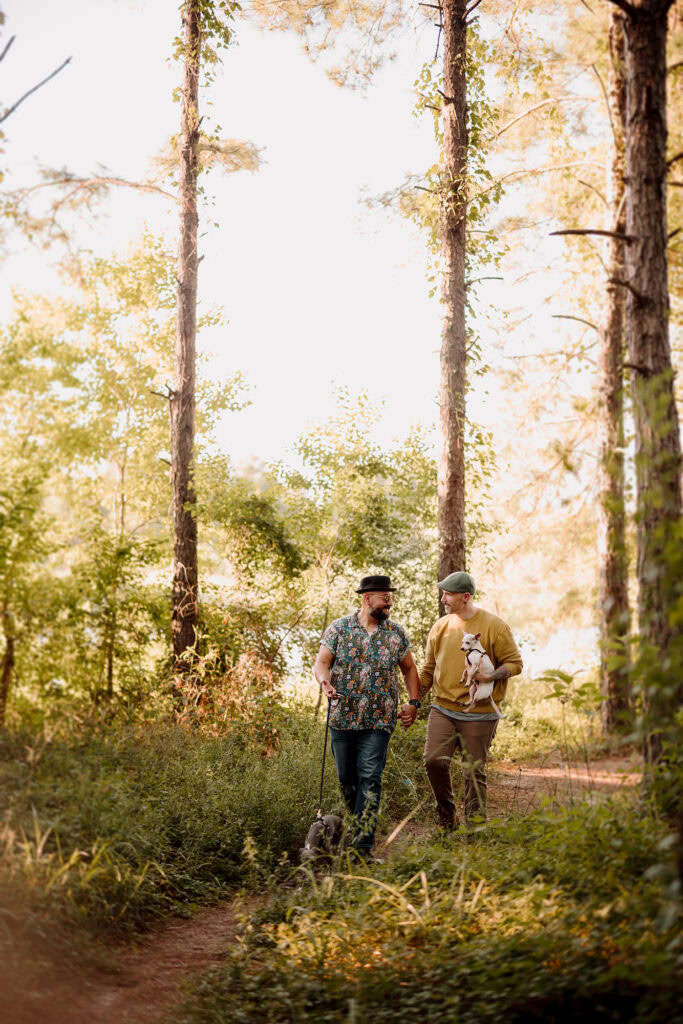 Two men walking in a sunlit forest, enjoying nature.