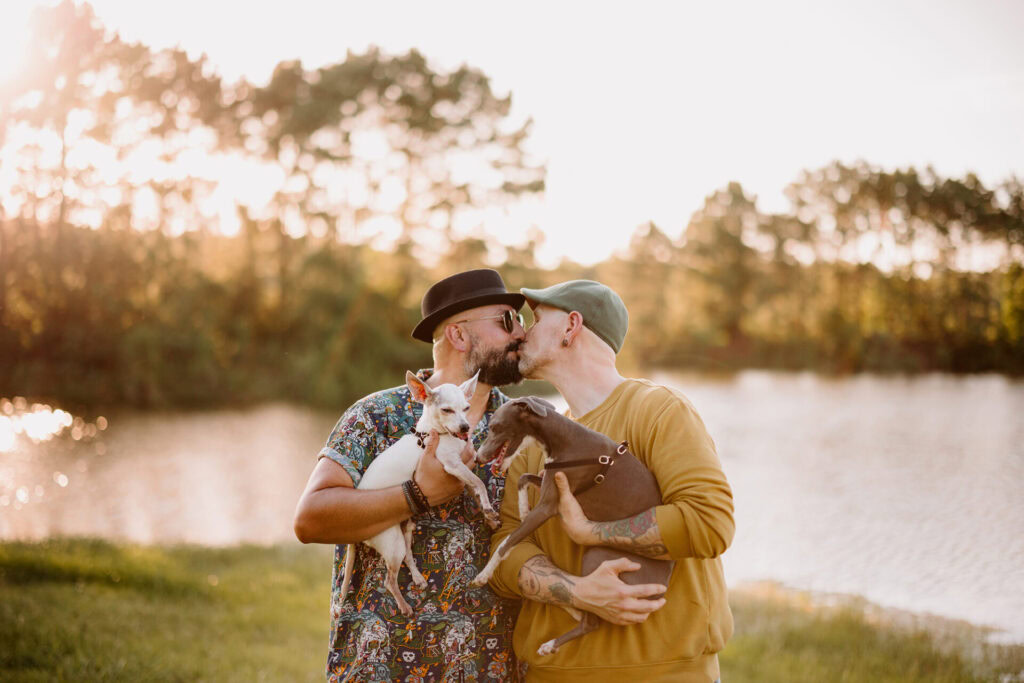 A couple sharing a kiss outdoors by the water at sunset.