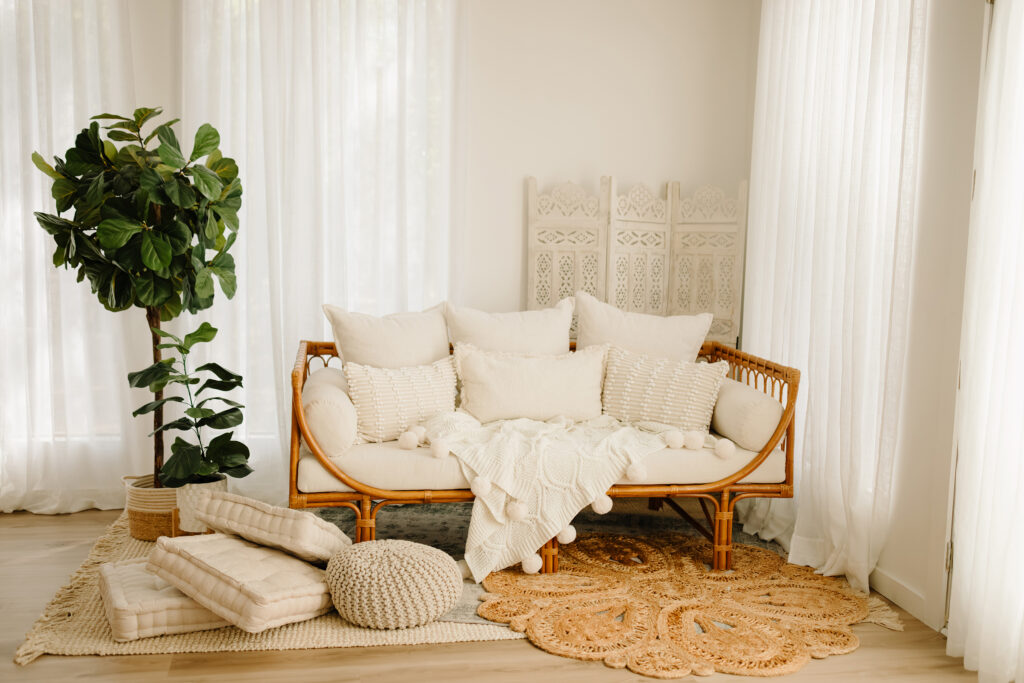 Cozy studio living room featuring a rattan sofa with plush cushions, soft throws, and natural decor.