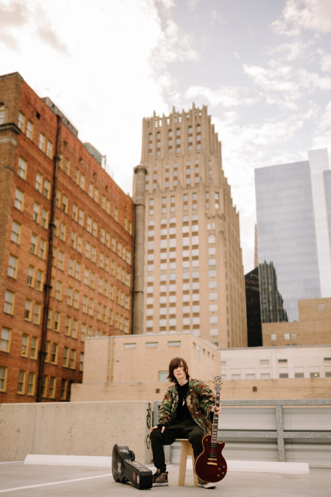 Urban skyline with a musician sitting on a bench.