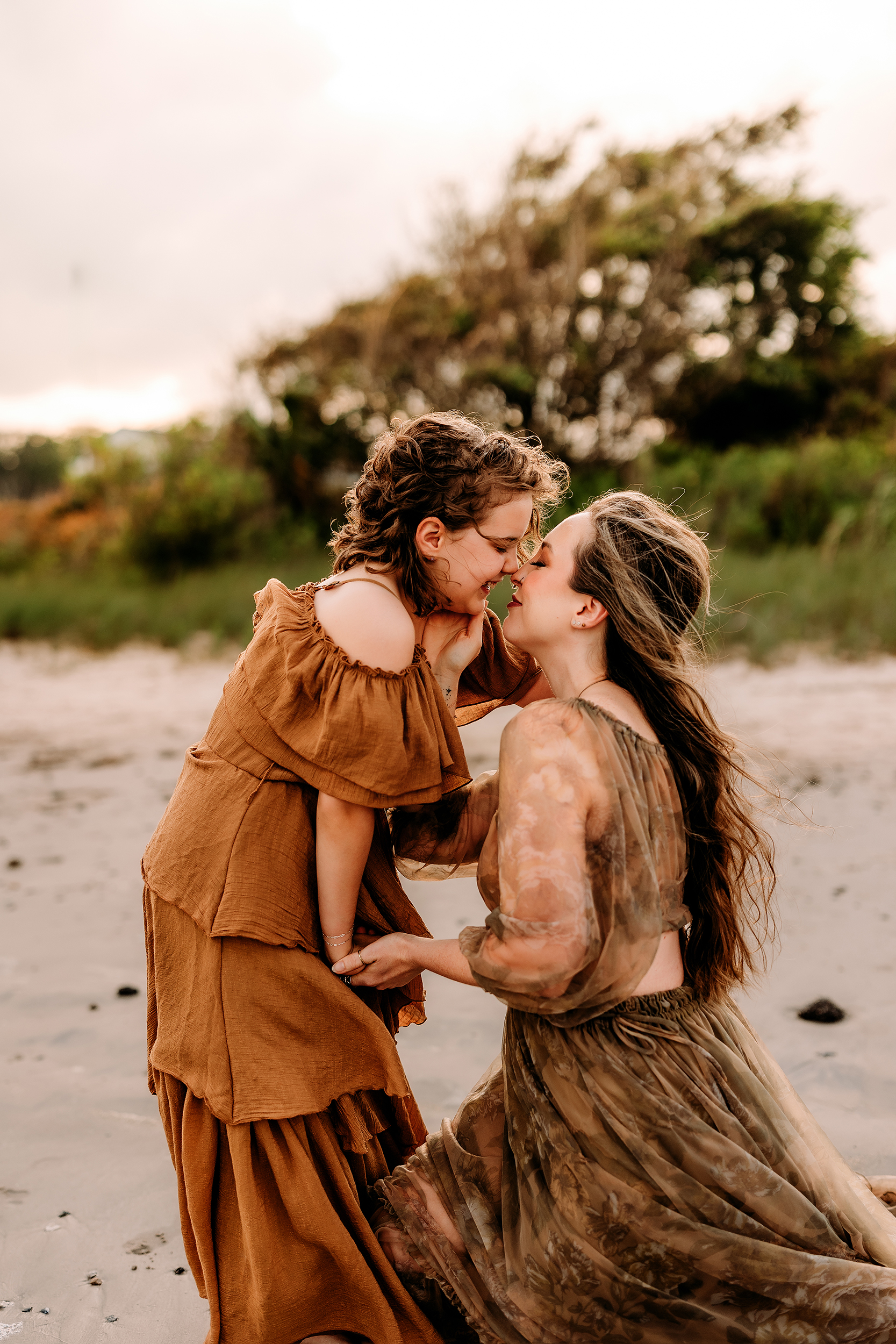 Two women sharing a tender moment on the beach, embracing each other.