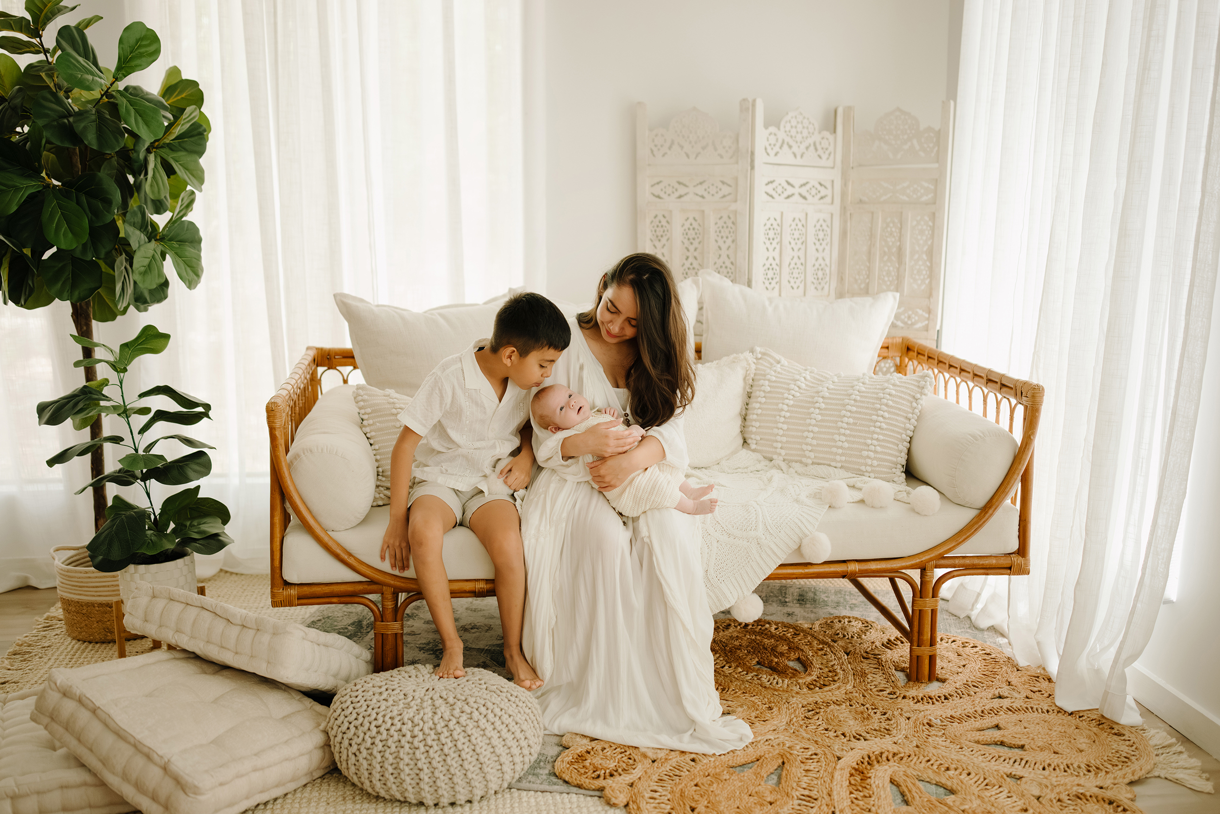 Family with two children sitting on a white sofa in a bright, airy room.